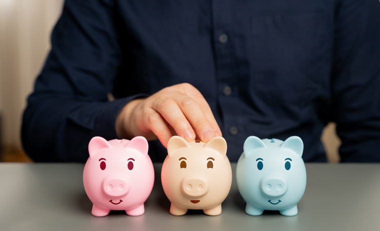 A man arranges a line of different colored piggy banks.