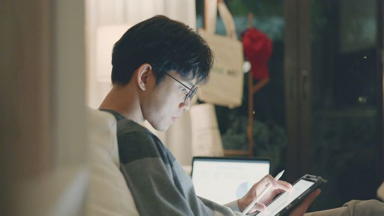 A man who's interested in adding more passive income assets to his portfolio looks over several dividend stocks on his tablet.