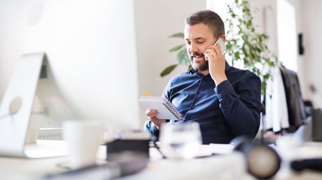 A company's financial manager reviews some financial data during a phone call with a colleague.