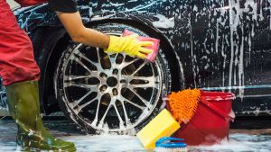 A car wash employee scrubs the rims of a car.