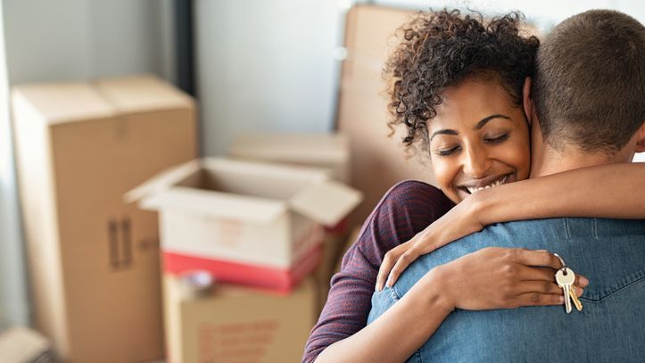 A woman hugs her husband as they move into the new home they just purchased.