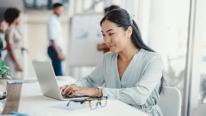 A 25-year-old woman types an email while at work.