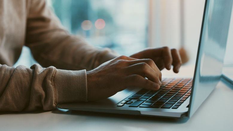 A financial advisor works on a blog post on his laptop.