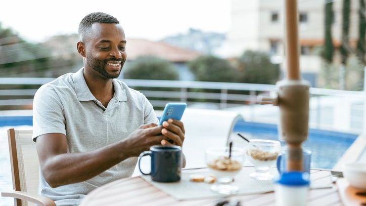 A man who has reached financial independence looks over his investment portfolio on his phone.