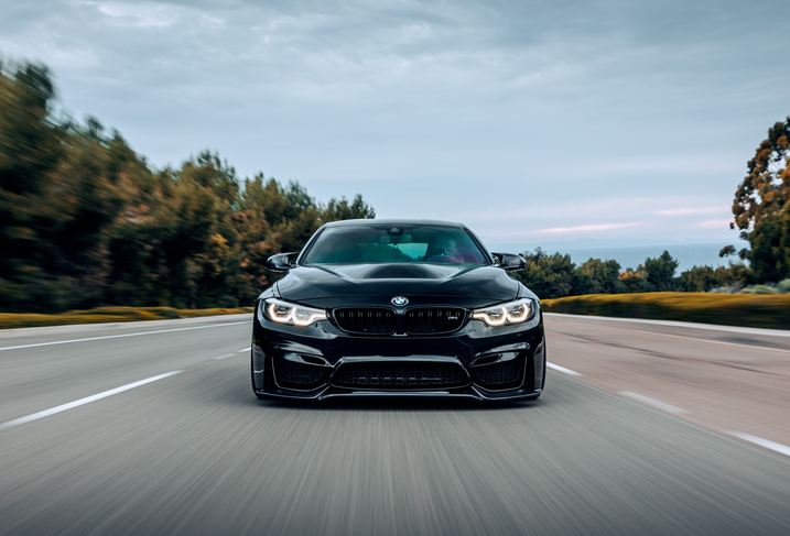 A black BMW M4 driving on the street without any other cars around.