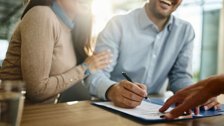 A couple signs mortgage documents on an investment property they're purchasing with $200,000 they have saved.