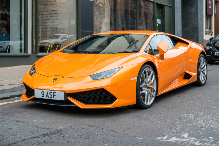 An orange colored Lamborghini Huracan sports car parked on a street.