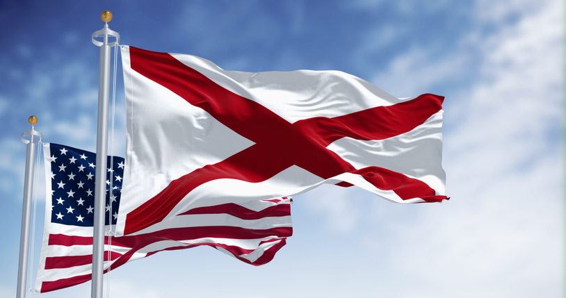 United States and Alabama flags waving together.