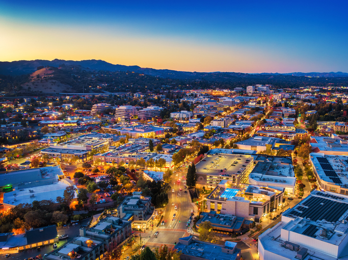 Downtown Walnut Creek at dusk, with mountains and the sunset in the background. Walnut Creek is part of the San Francisco Bay Area.