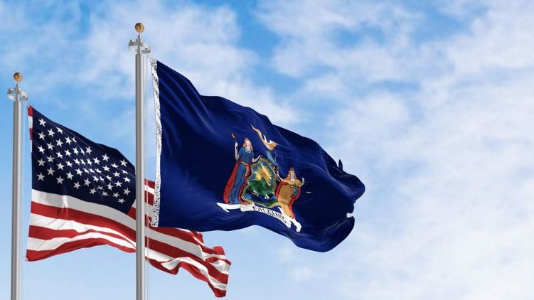 The New York state and American flags blow in the wind.