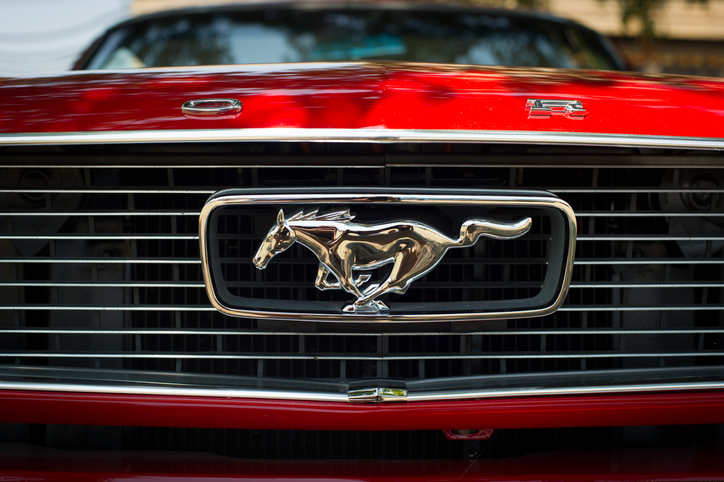 A Ford red Mustang horse logo on front of a car.
