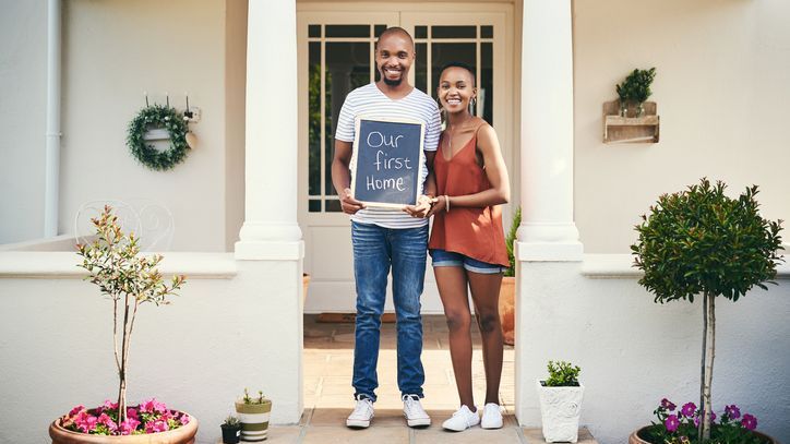 A young couple poses for a photo after buying their first home together.