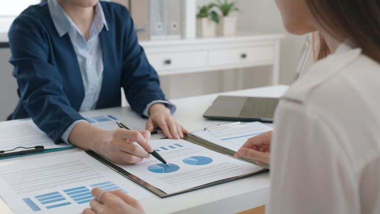 Two people review pie charts and other data.