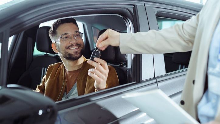 A man hands the keys to his car to a person who is renting it for the day.