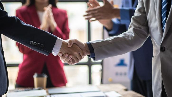 Financial advisors shake hands after agreeing to a management buyout of an advisory practice.