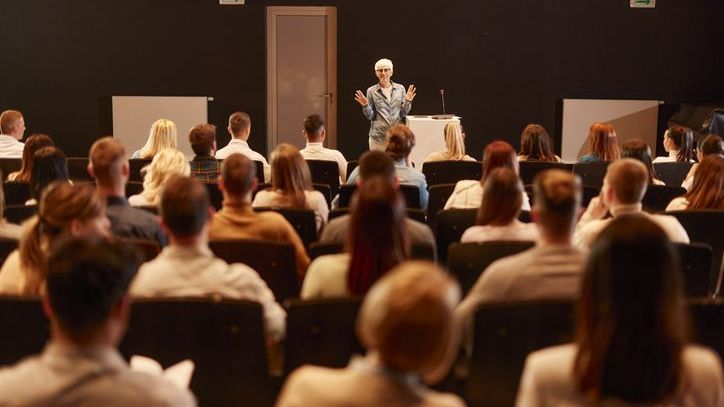 A woman speaks to the attendees of a conference.