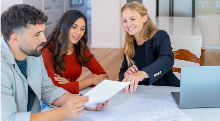 A couple who's buying their first home reviews paperwork with their real estate agent.