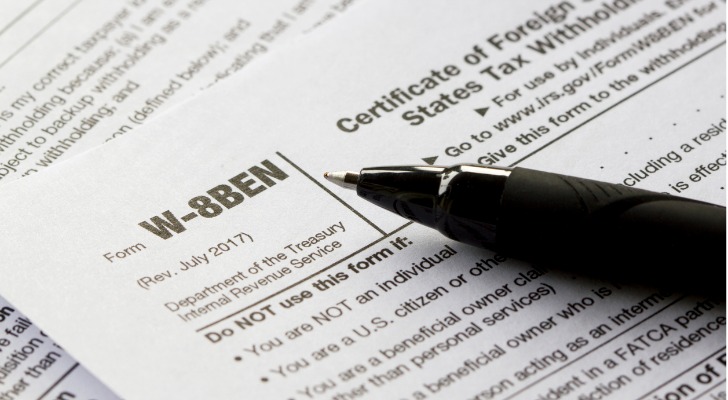 A pen sits on top of Form W-8BEN.