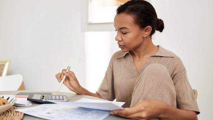 A woman uses a calculator while doing her taxes at home.