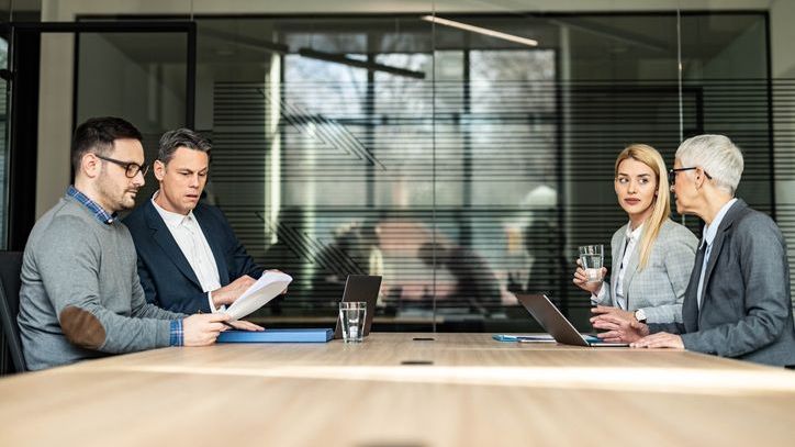 A couple sits across from each other at a conference table accompanied by their lawyers.