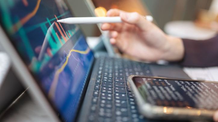 A person touches their laptop screen with a pen.