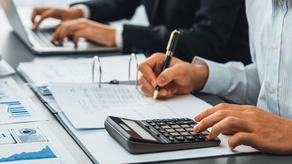 A close-up of a man analyzing financial data and doing calculations.