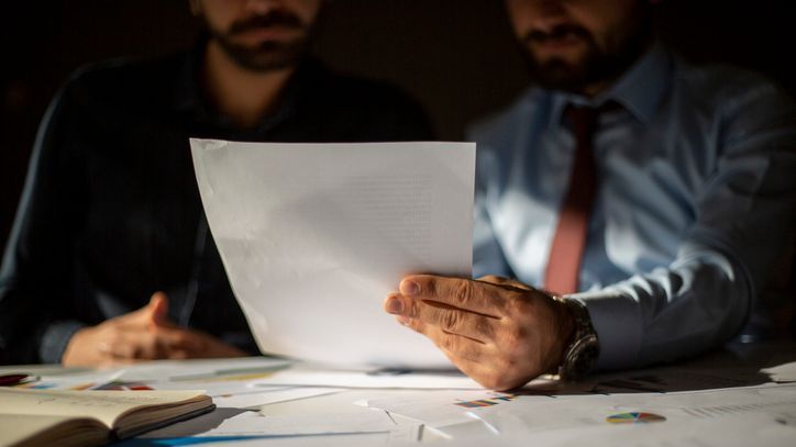 Two men go over paperwork together.