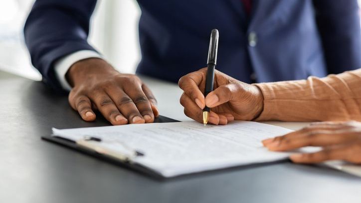 A closeup image of a person signing a contract.