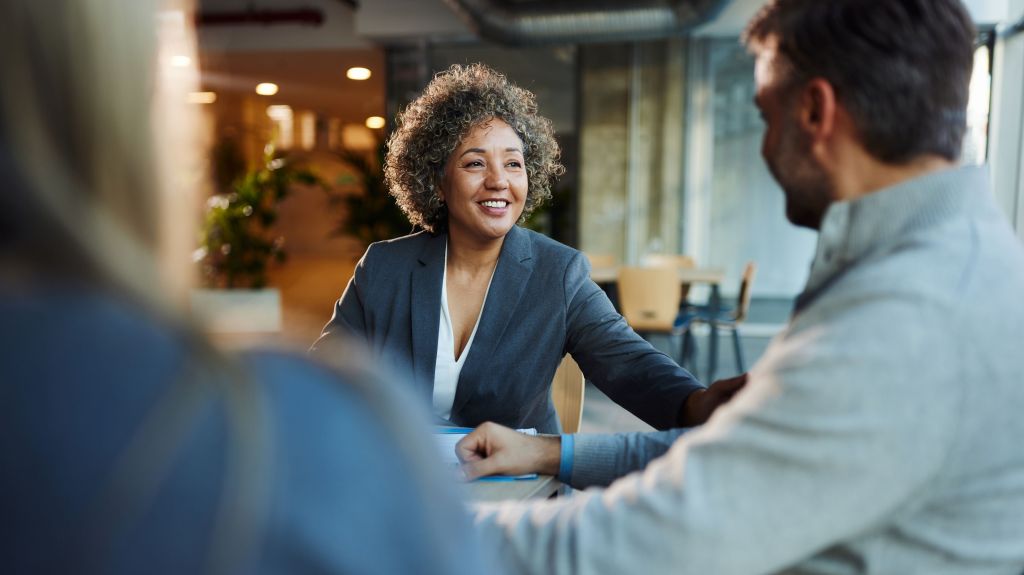 A businesswoman speaks with her colleagues during a meeting in their office.