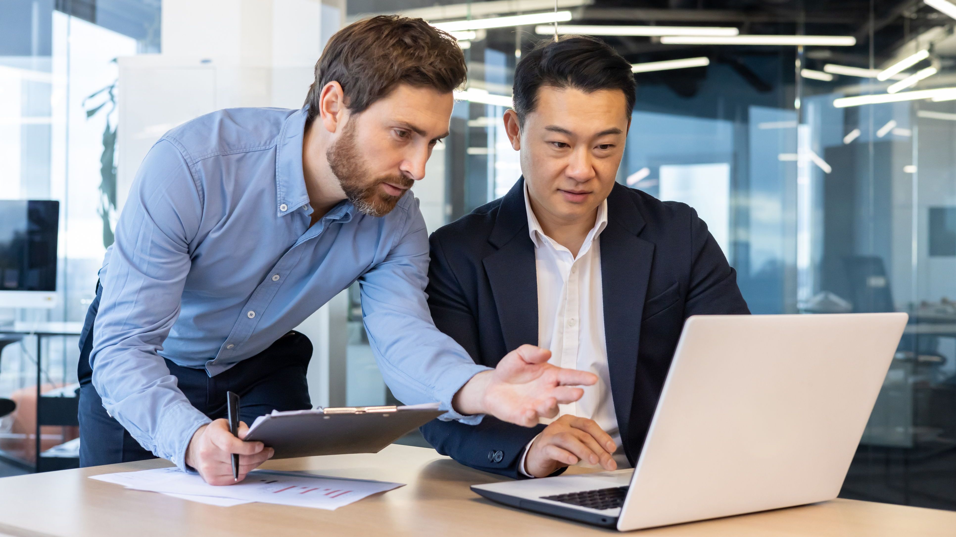 Colleagues review financial data on a laptop.