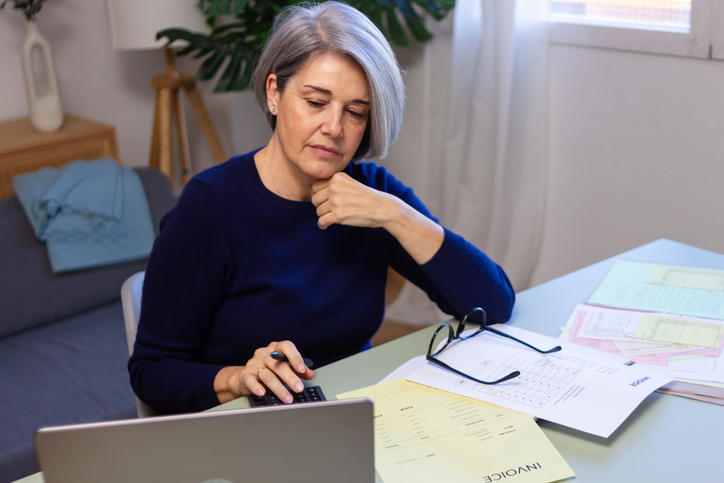 A woman calculating how much she will need for retirement with the $1,000 a month rule.
