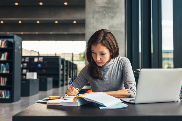 A young woman studies for the Securities Industry Essentials (SIE) Exam.