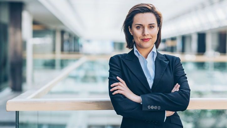 A woman in business wear standing with her arms crossed.