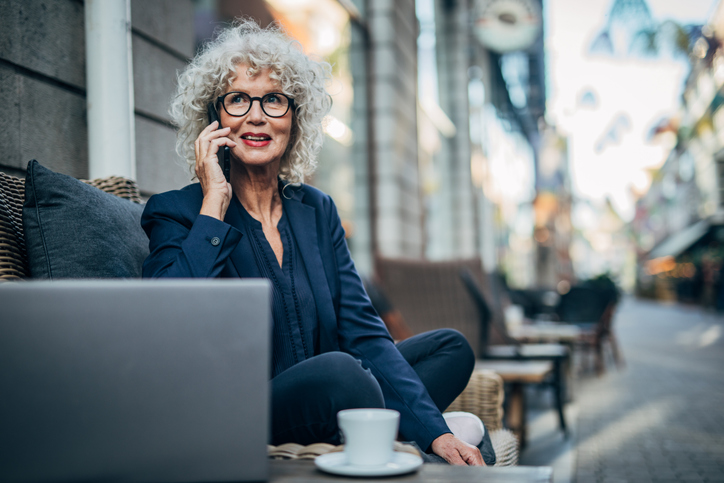 A senior business woman discussing with her advisor on the phone a strategy to retire at age 80.