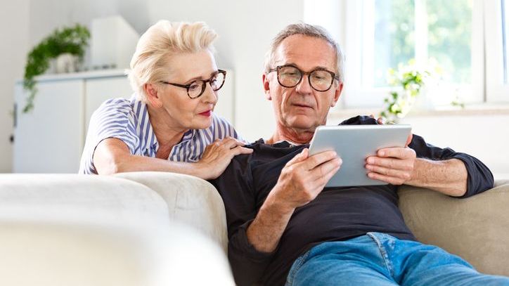 A man and woman review some paperwork on a tablet.