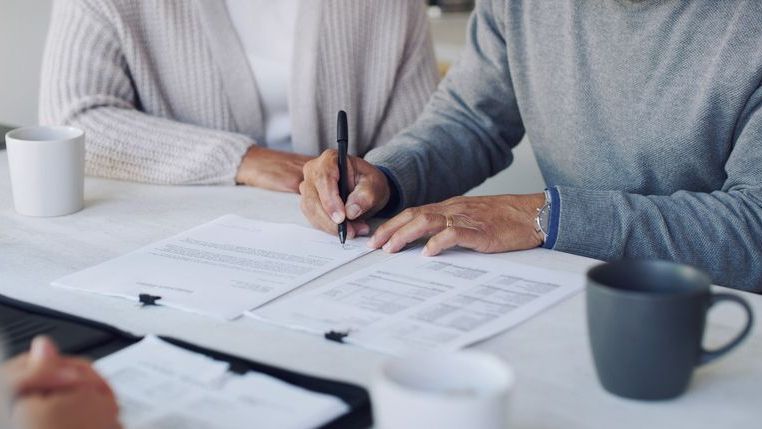 Cropped shot of a senior couple signing paperwork together.