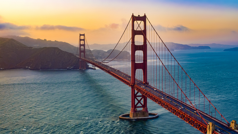 An aerial view of traffic moving on Golden Gate Bridge during sunset.
