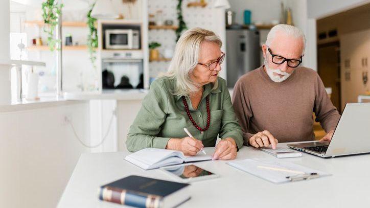 A senior couple look over their budget together in their home.