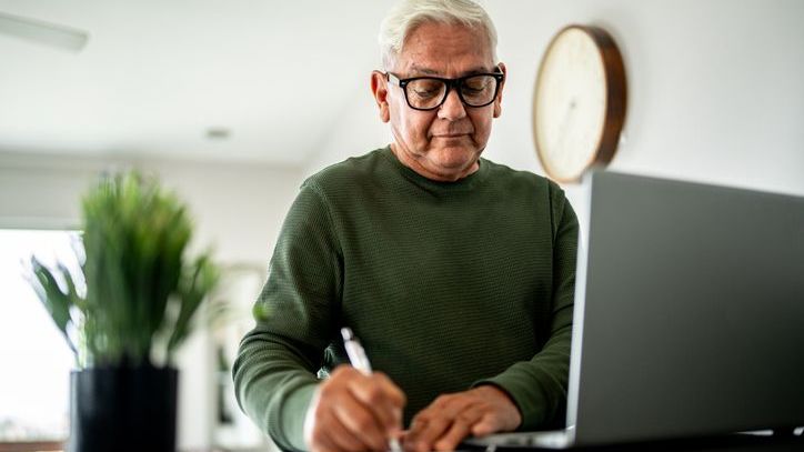 A senior man using computer and reviewing his finances at home.