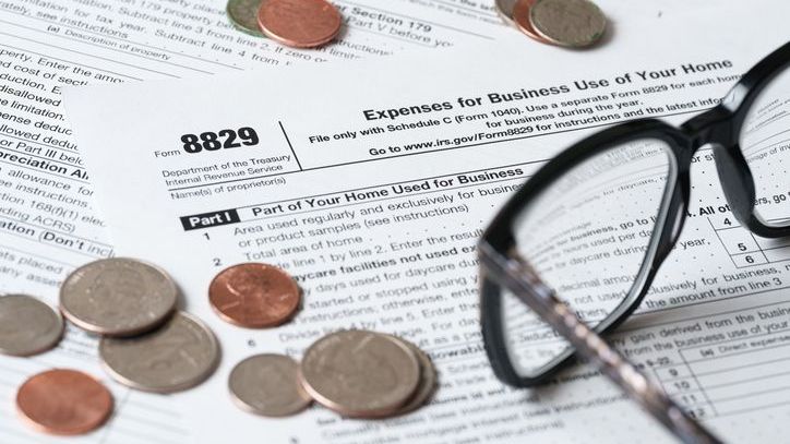 A pair of glasses and several coins sit on top of Form 8829.