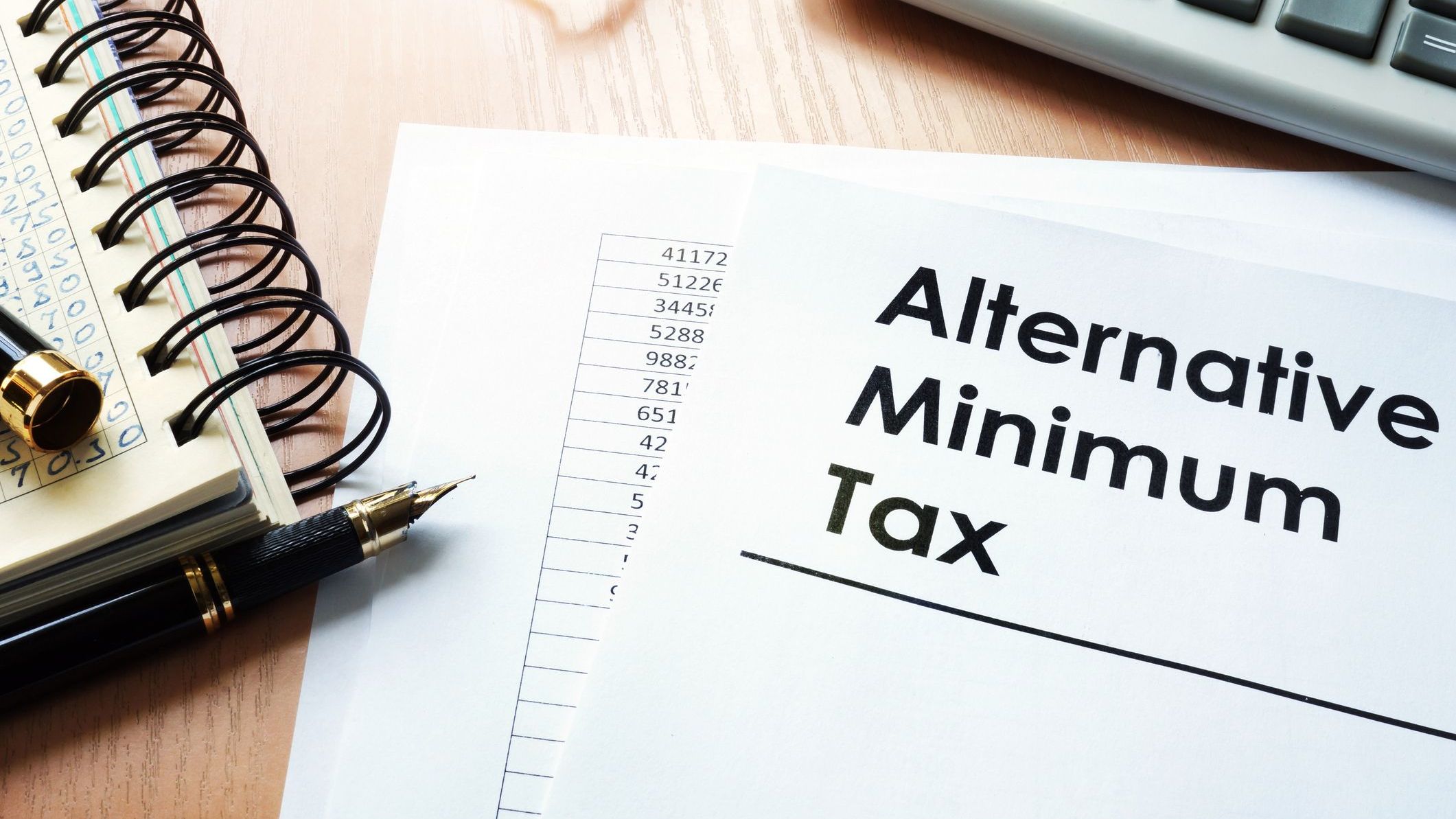 A closeup image of a piece of paper with "Alternative Minimum Tax" in bold lettering on a desk.