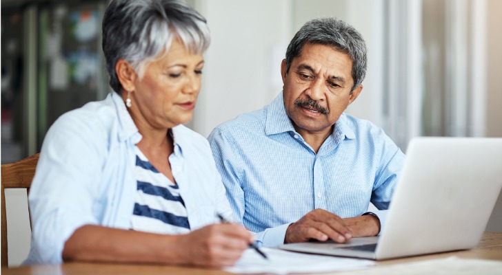 A senior couple using a laptop to do their household budget.