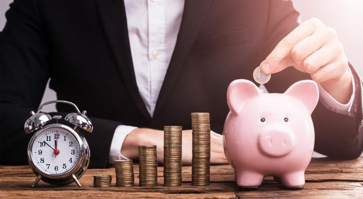 Closeup of an alarm clock, stacks of coins and a piggy bank to represent retirement savings.