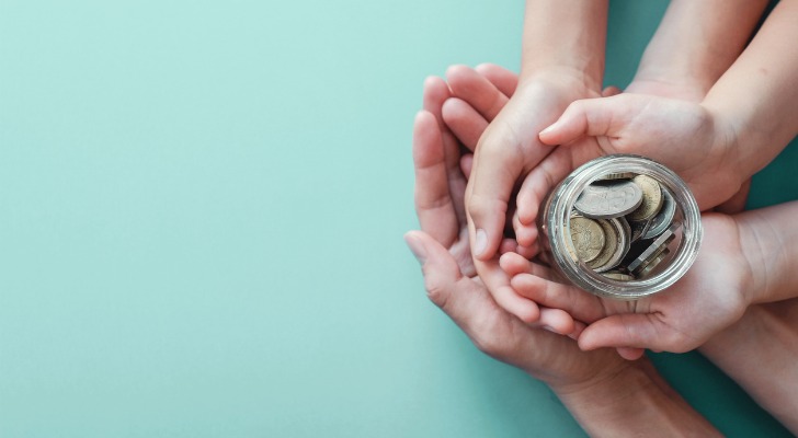 Closeup of different pairs of hands from youngest to oldest holding a coin jar for savings.