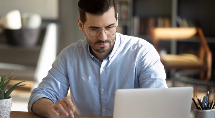 A middle-aged man working on a laptop computer.