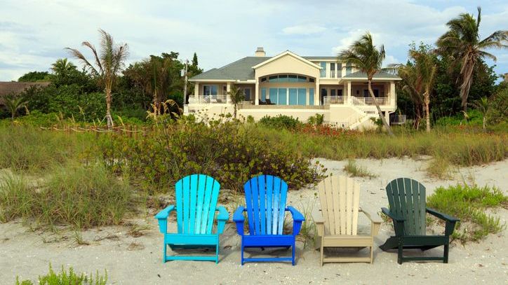 Adirondack chairs arranged in front of a yellow beach house in Captiva Island, Florida.