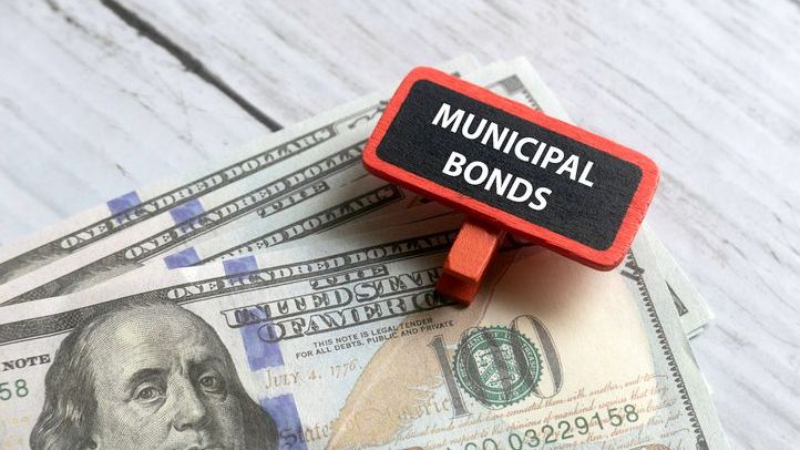 A close-up image of dollar notes and a red tag that reads "MUNICIPAL BONDS."