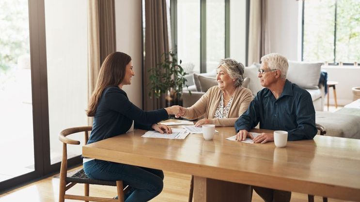 A financial advisor shakes hands with a senior couple.