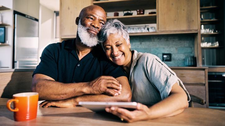 A senior couple happily reviews their retirement plan while sitting at their kitchen table.