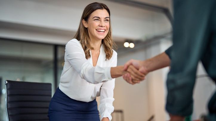 A woman shakes hands with a client in her office.